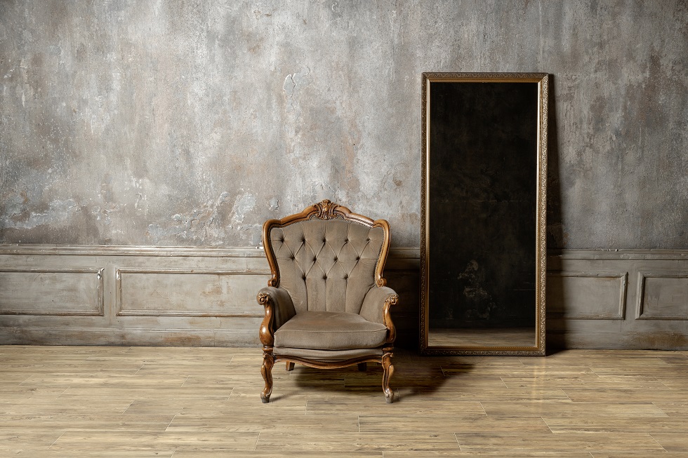 old chair and a mirror on the background of vintage wall